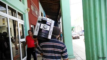 Hombre cargando en el hombro un equipo de música
