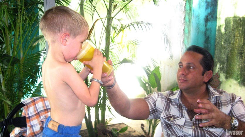 Padre ayudando a su niño a tomar jugo