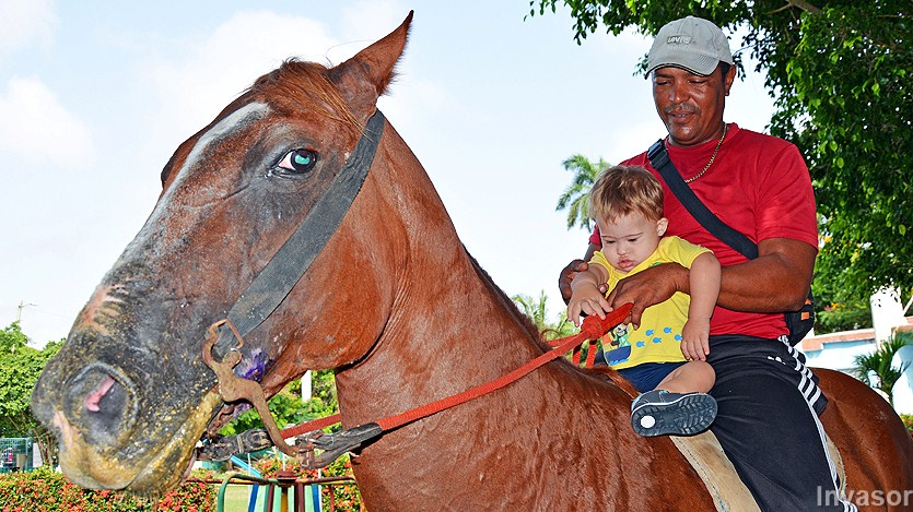 Niño paseando a caballo junto a entrenador