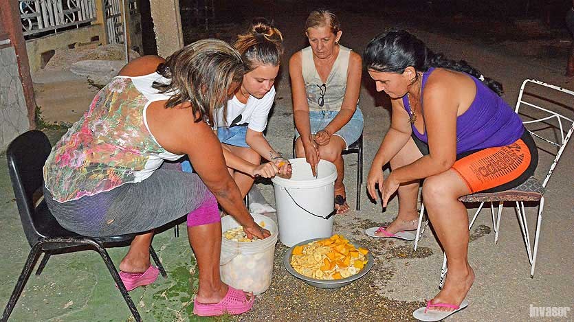 Mujeres sentadas preparando viandas para caldosa