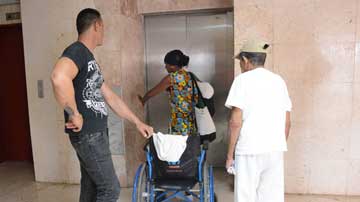 Personas en salón, sillas de ruedas en segundo plano, ascensor en tercer plano