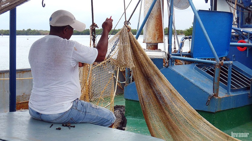 Pescador cosiendo redes