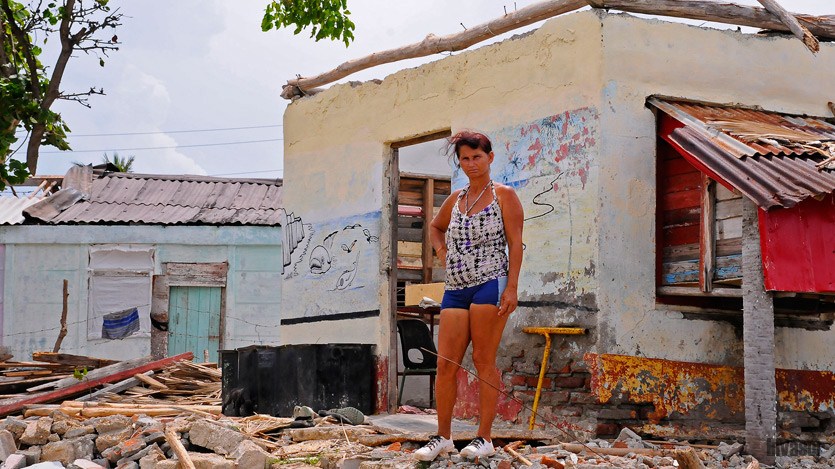 Mujer frente a vivienda destruida